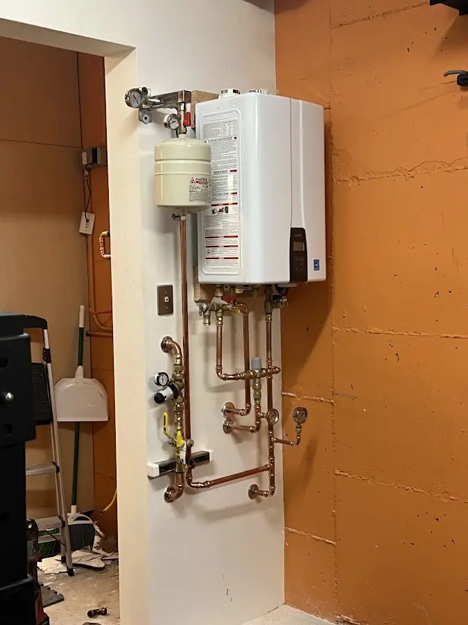 Plumbing technician inspecting water heater connections in New Hartford
